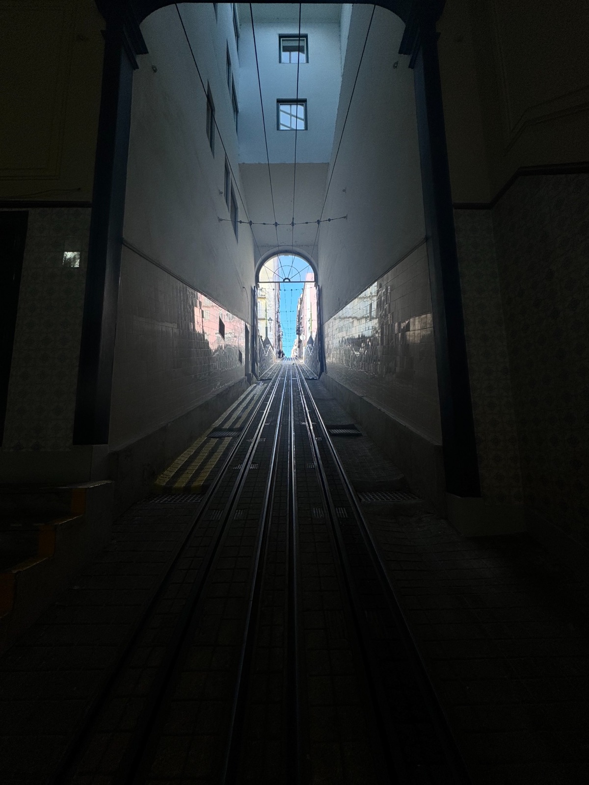 Funicular rails leading through a dark passage toward daylight