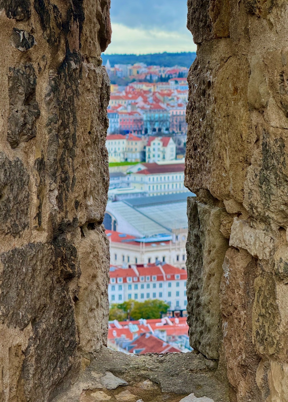 City rooftops framed by an opening in a stone wall