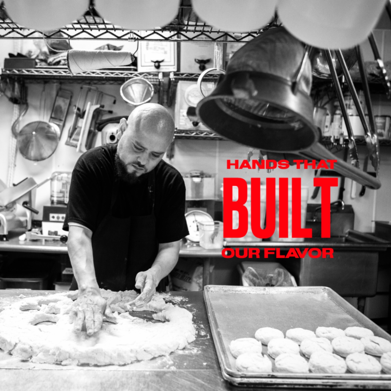 Black-and-white kitchen portrait with red Hands that built our flavor lettering