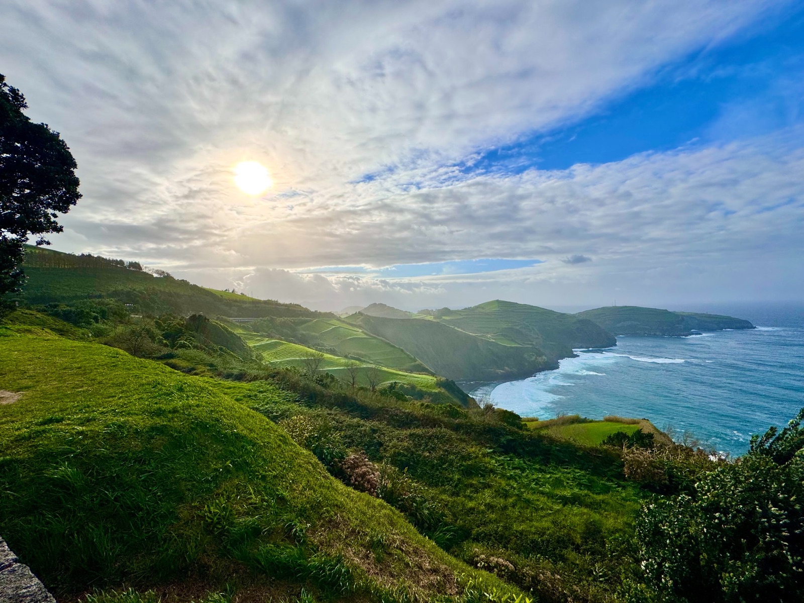 Sunlight over rolling green coastal hills and blue ocean